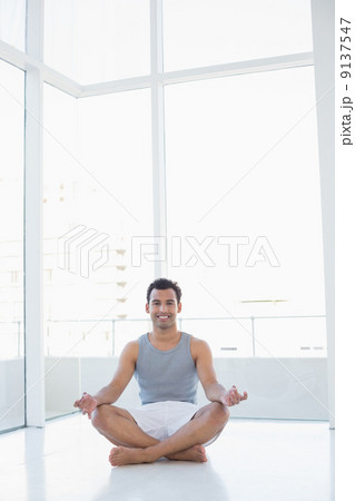 Full length portrait of a smiling man sitting in lotus pose Full length portrait of a smiling man sitting in lotus pose 9137547
