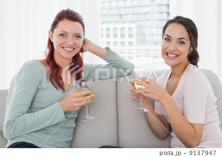 Young female friends with wine glasses at home 9137947