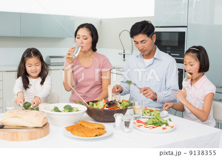 Young family of four enjoying healthy meal in kitchen Young family of four enjoying healthy meal in kitchen 9138355