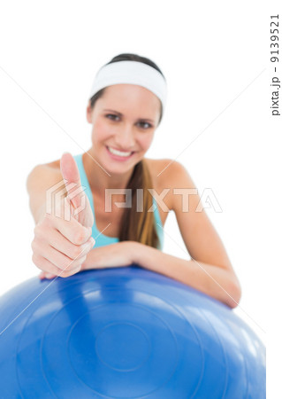 Smiling fit woman with fitness ball gesturing thumbs up Smiling fit woman with fitness ball gesturing thumbs up 9139521