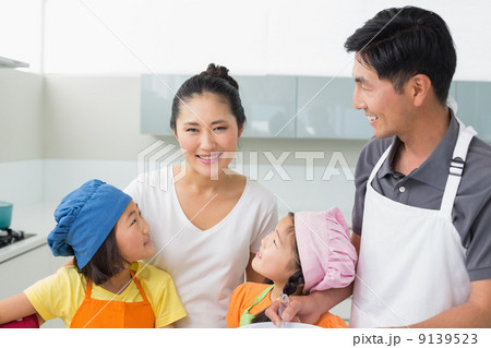 Happy family of four smiling in kitchen 9139523