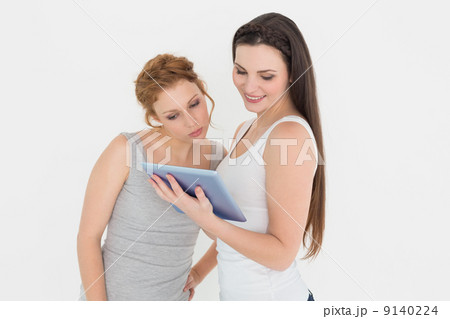 Two casual young female friends with digital tablet Two casual young female friends with digital tablet 9140224