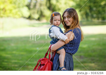 Beautiful mother and little daughter walking in summer park Beautiful mother and little daughter walking in summer park 9163284