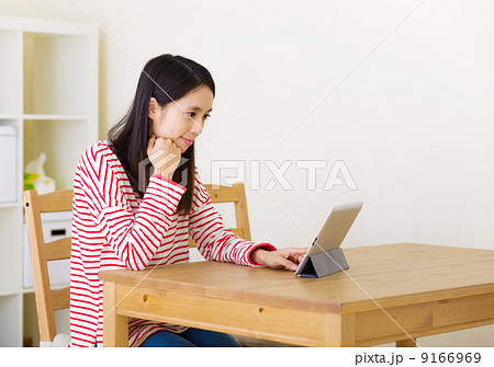 Asian woman using digital tablet at home Asian woman using digital tablet at home 9166969