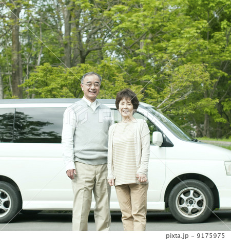 車の前で微笑むシニア夫婦 9175975