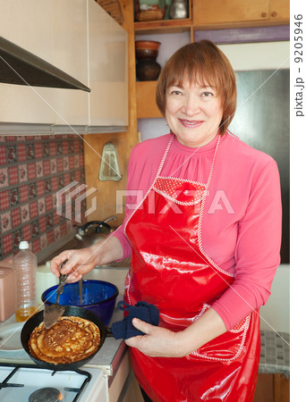 Mature woman cooking pancakes Mature woman cooking pancakes 9205946