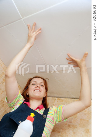 Woman glues ceiling tile 9206693