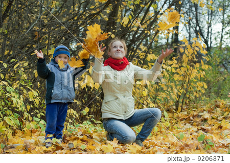 mother with boy throwing maple leaves mother with boy throwing maple leaves 9206871