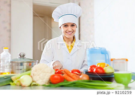 cook woman in uniform cutting vegetables 9210259