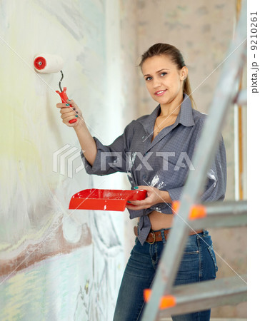 woman paints wall with roller at home 9210261