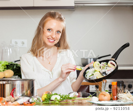Smiling woman cooking fish with lemon 9211058