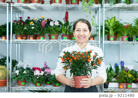 mature woman with citrus plant in store 9211480