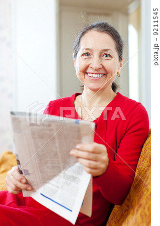 cheerful mature woman with newspaper 9211545