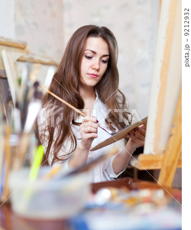 Long-haired artist paints on canvas 9212932