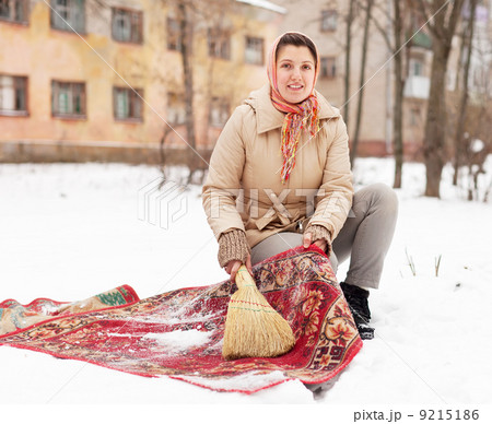 woman cleans rug with snow 9215186