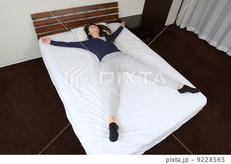 大の字になって寝る若い女性 9228565