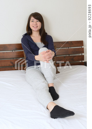 ベッドの上でリラックスする若い女性 9228693