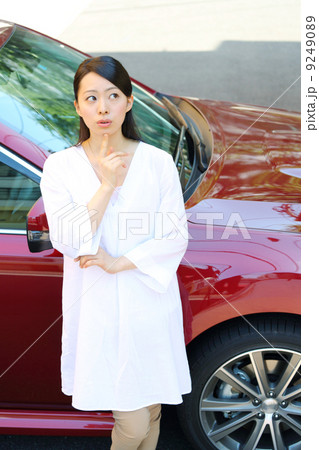 車の前で悩む女性の写真素材