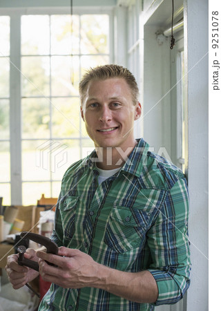 A man in a workshop, holding a carpenter's clamp in his hand. A man in a workshop, holding a carpenter's clamp in his hand. 9251078