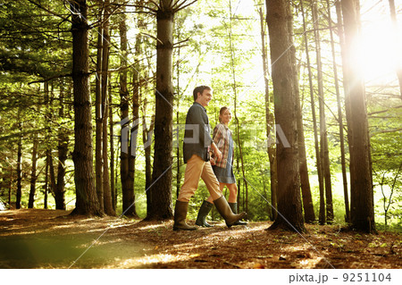 Three people, a family walking in woodland in the late afternoon. Three people, a family walking in woodland in the late afternoon. 9251104