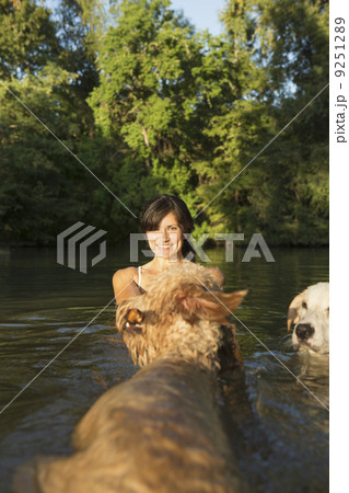 A woman swimming with her two dogs in a lake.  9251289