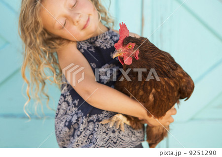 A young girl holding a chicken in her arms.  9251290