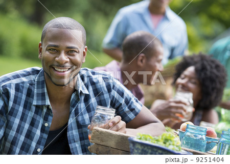 A group of adults and young people at a meal in the garden of a farmhouse.  9251404