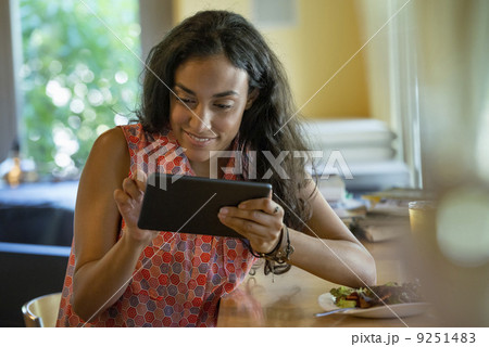A person sitting alone in a cafe. A woman using a digital tablet. 9251483
