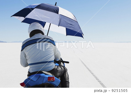 A motorcyclist sheltering under an umbrella, on the start line at Speed Week, on the Bonneville Salt Flats.  9251505