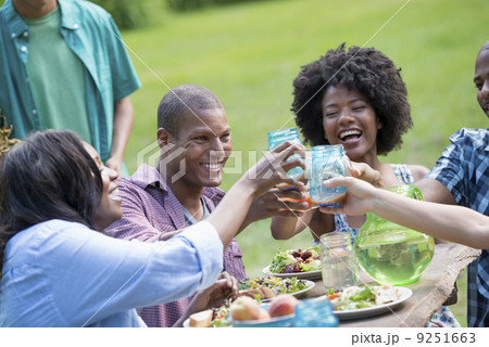 A group of adults and young people at a meal in the garden of a farmhouse.  9251663