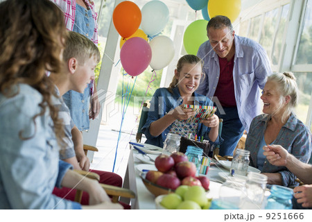 A birthday party in a farmhouse kitchen. A group of adults and children gathered around a chocolate cake. A birthday party in a farmhouse kitchen. A group of adults and children gathered around a chocolate cake. 9251666