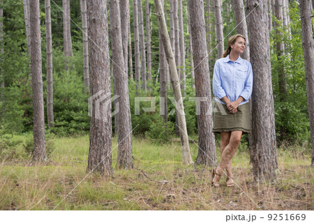 A woman standing among the trees on the shore of a lake in New York state. A woman standing among the trees on the shore of a lake in New York state. 9251669