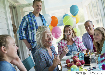 A birthday party in a farmhouse kitchen. A group of adults and children gathered around a chocolate cake. A birthday party in a farmhouse kitchen. A group of adults and children gathered around a chocolate cake. 9251767