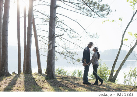 Lakeside. A couple walking in the shade of pine trees in summer. Lakeside. A couple walking in the shade of pine trees in summer. 9251833