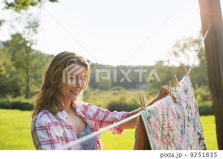 A woman hanging laundry on the washing line, in the fresh air.  9251835