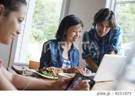 A group of three people in a cafe. Sharing a laptop and using smart phones. A group of three people in a cafe. Sharing a laptop and using smart phones. 9251973
