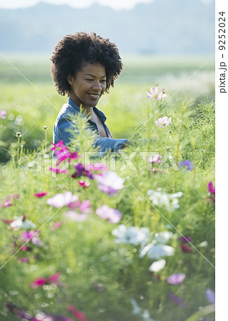 A woman standing among the flowers growing in the fields. A woman standing among the flowers growing in the fields. 9252024