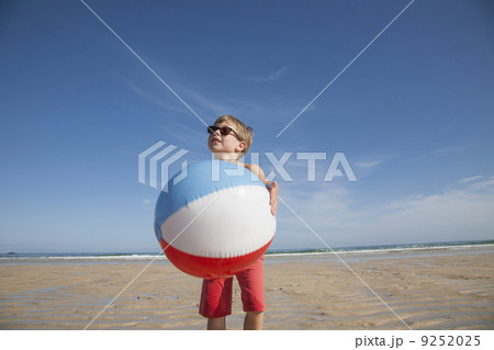 A boy on the beach holding a large inflatable beach ball.  9252025