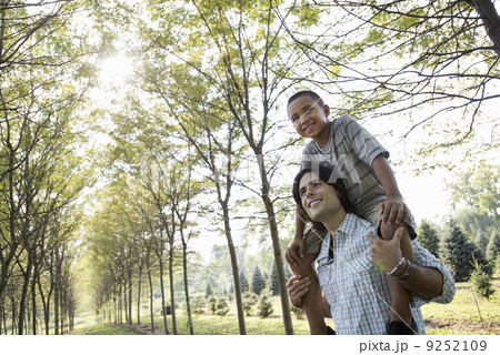 A man giving a boy a piggyback in the woods. A man giving a boy a piggyback in the woods. 9252109