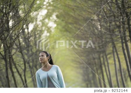 A woman between two rows of trees, looking upwards. A woman between two rows of trees, looking upwards. 9252144