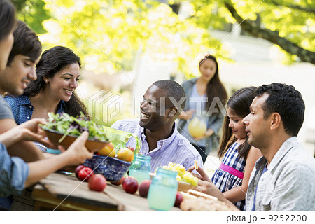 Adults and children around a table in a garden. Adults and children around a table in a garden. 9252200