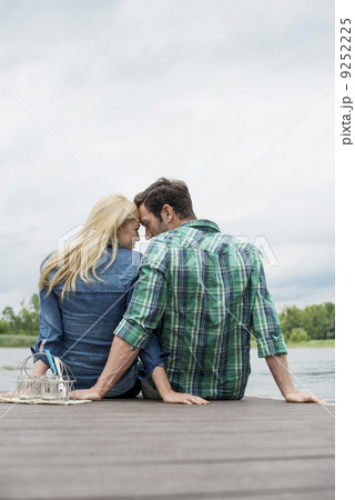 A man and woman seated on a jetty by a lake. A man and woman seated on a jetty by a lake. 9252225