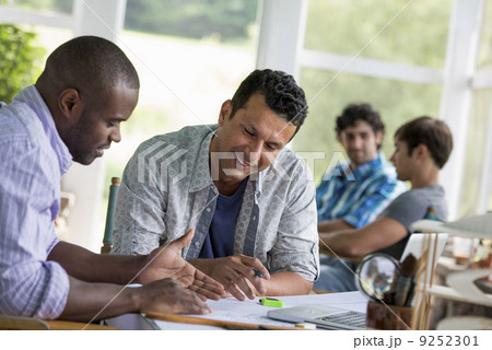 Two men seated, working together. 9252301