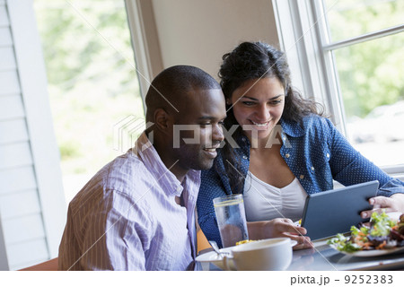 A couple seated looking at a digital tablet. 9252383