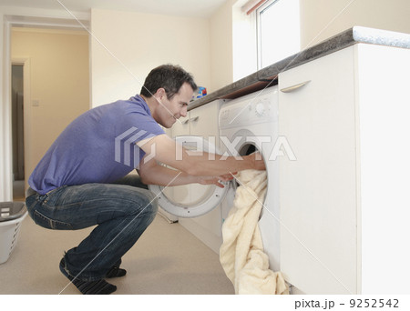 A man putting the laundry into the washing machine. A man putting the laundry into the washing machine. 9252542