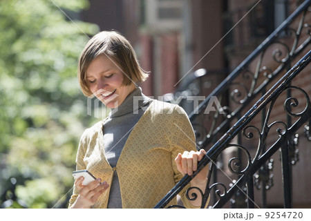 City. A Woman On Steps Outside A Townhouse, Checking Her Smart Phone.  9254720