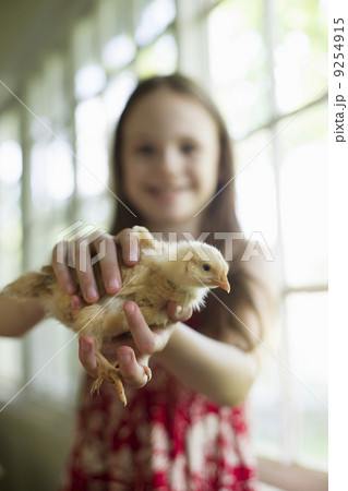 A Young Girl In A Floral Sundress, Holding A Young Chick Carefully In Her Hands. 9254915