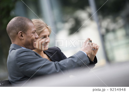 A Young Blonde Woman And A Man On A New York City Street. Wearing Business Clothes. Standing Side By Side Taking A Selfy Photograph With A Smart Phone. A Young Blonde Woman And A Man On A New York City Street. Wearing Business Clothes. Standing Side By Side Taking A Selfy Photograph With A Smart Phone. 9254948