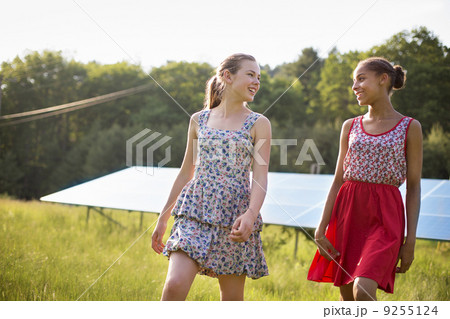 Two Young Girls On The Farm, Outdoors. A Large Solar Panel In The Field Behind Them. Two Young Girls On The Farm, Outdoors. A Large Solar Panel In The Field Behind Them. 9255124