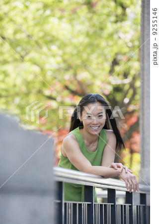 A Woman In A Green Dress Outdoors In A City Park Under Trees In Blossom. 9255146